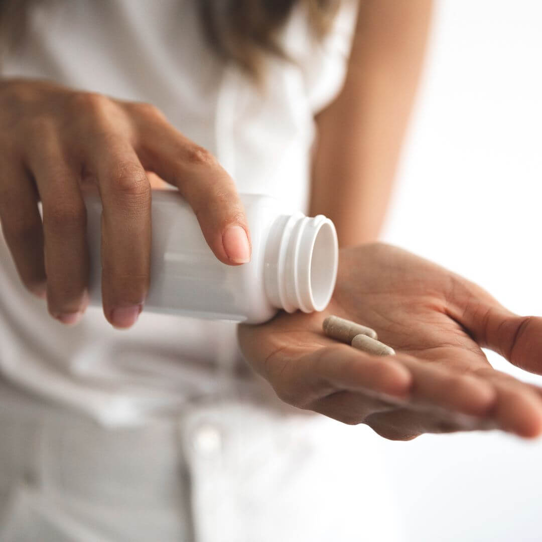 woman putting capsules from a jar into hand