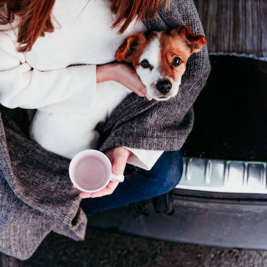 woman drinking warm drink and holding dog