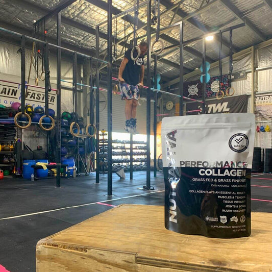 cross fitter doing muscle up in background performance collagen pack on box in foreground