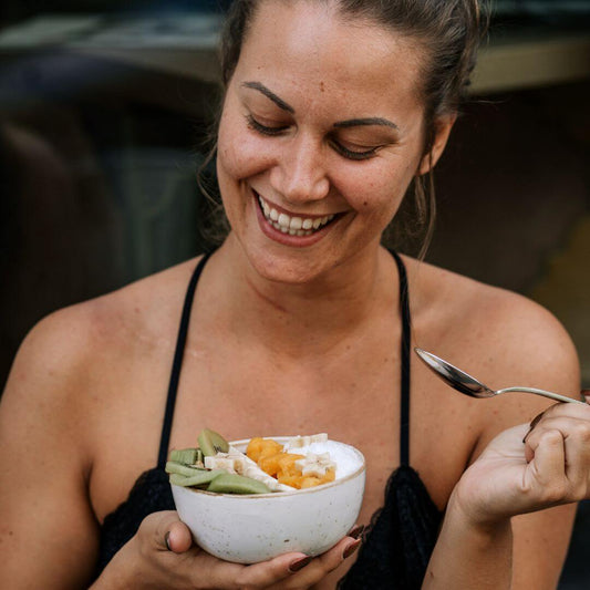 lady smiling and about to spoon  into a yogurt and fruit bowl