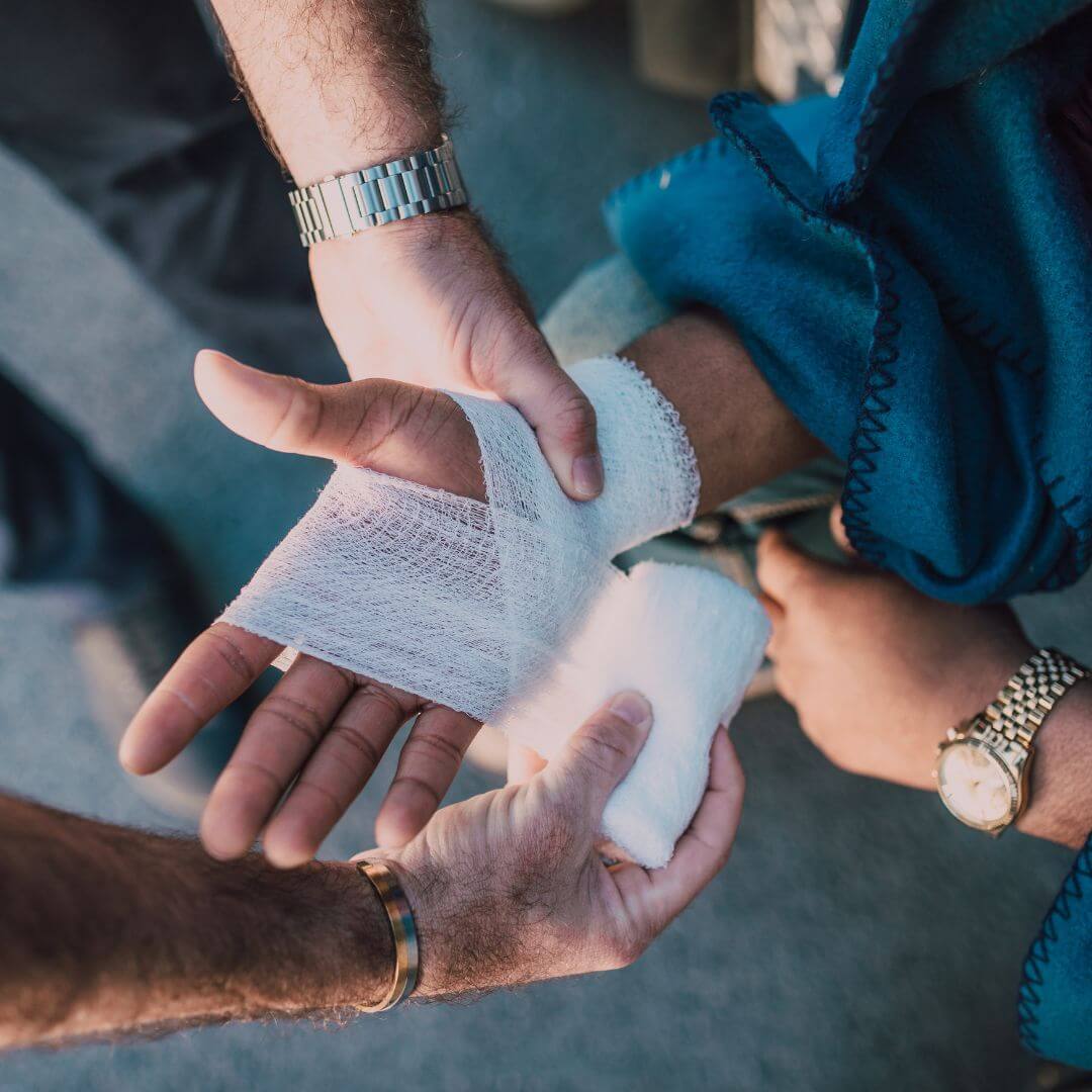 person wrapping another persons hand with a bandage