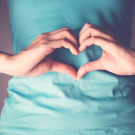 person holding heart hands in front of their stomach