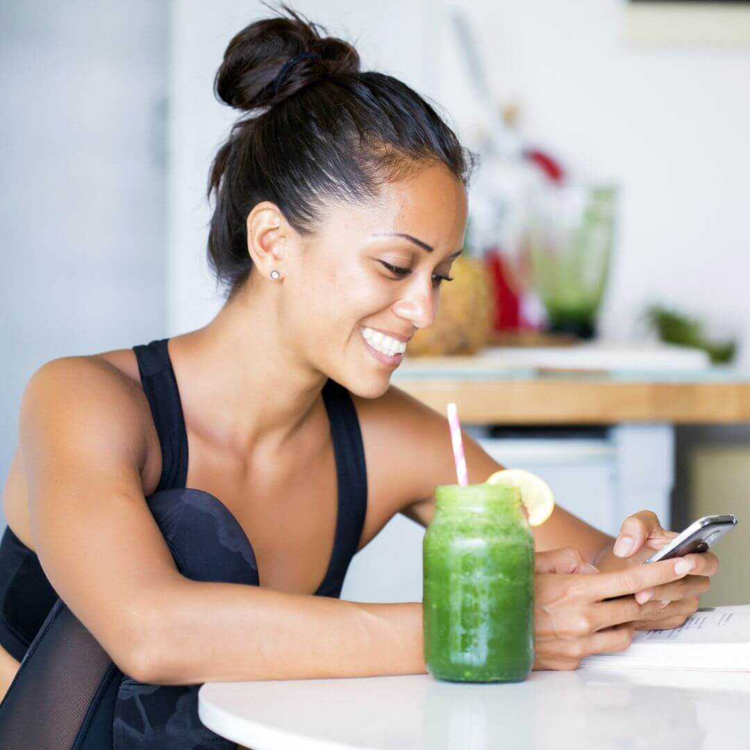 healthy woman researching on phone with smoothie