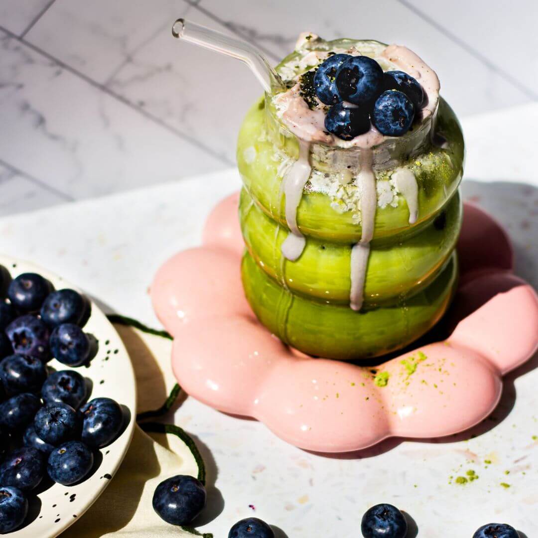 matcha collagen smoothie in a cloud glass with blueberries on the side